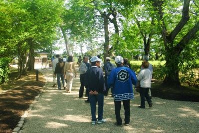 客に庭園内をガイドする顕彰会員、画像をタップすると顕彰会を紹介するページに移動します